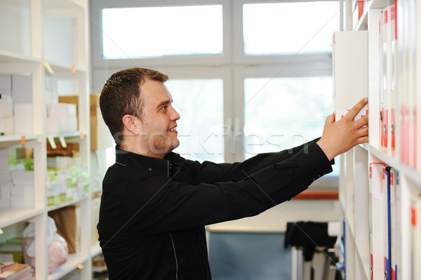 Man working at office putting folders together on shelves Stock photo © zurijeta