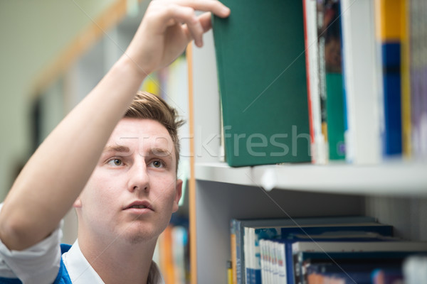 Happy young students studying in college library picking a book  Stock photo © zurijeta