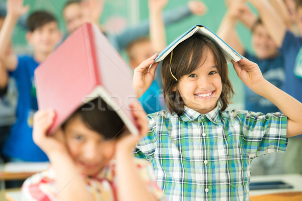 Group of children with books on heads smiling in classroom Stock photo © zurijeta