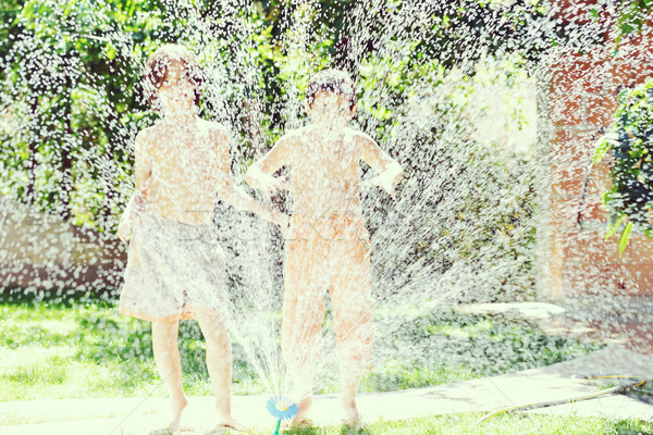 Children playing and splashing with water sprinkler on summer gr Stock photo © zurijeta