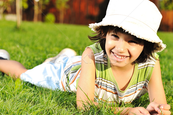 Cute kid with hat on head laying on grass in park Stock photo © zurijeta