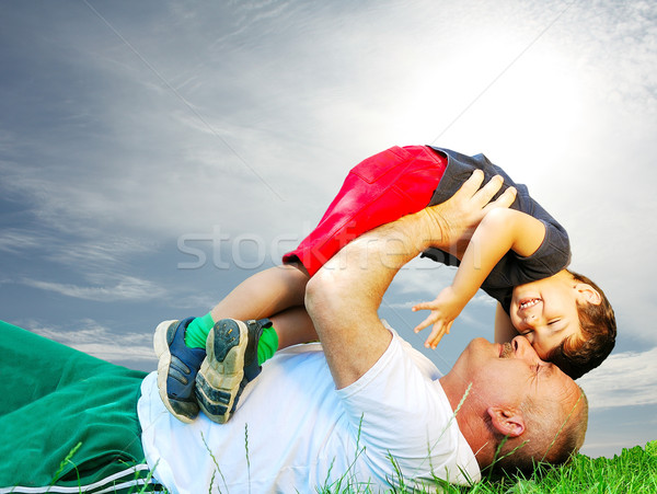 A grandfather and his kid laying and smiling on grass Stock photo © zurijeta