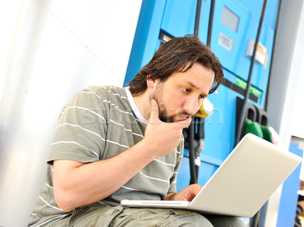 Man with laptop on gas station with silly expression on his face after reading last news Stock photo © zurijeta