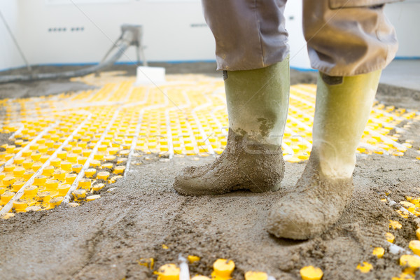 Stock photo: Plasterer at indoor concrete cement floor topping with float