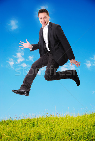 Stock photo: Young businessman jumping on green meadow