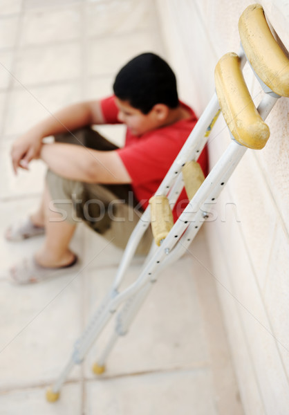  kid sitting  on the street with a crutches  Stock photo © zurijeta