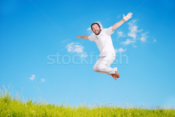Happy young mane in white jumping on beautiful meadow Stock photo © zurijeta