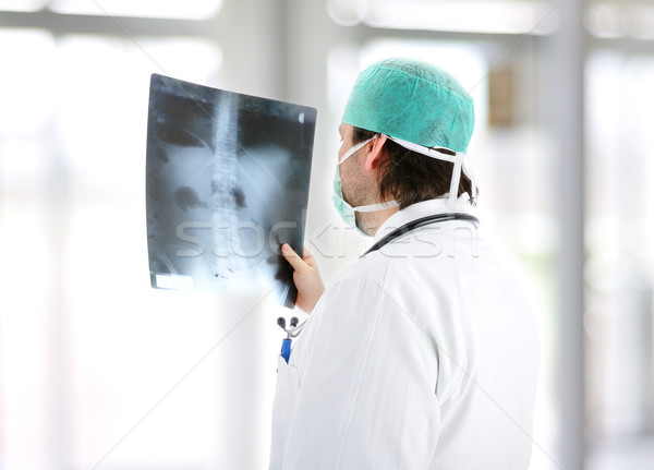 Medical doctor analysing x-ray image handheld, standing at office desk Stock photo © zurijeta