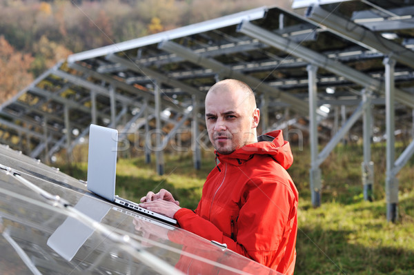 Male engineer using laptop, solar panels in background Stock photo © zurijeta