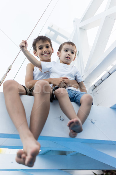 Cheerful little boy sitting on white bridge and enjoy Stock photo © zurijeta