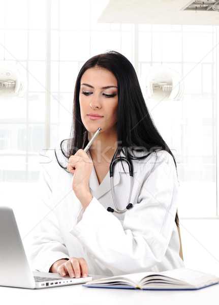 Young woman doctor in white coat at computer thinking Stock photo © zurijeta