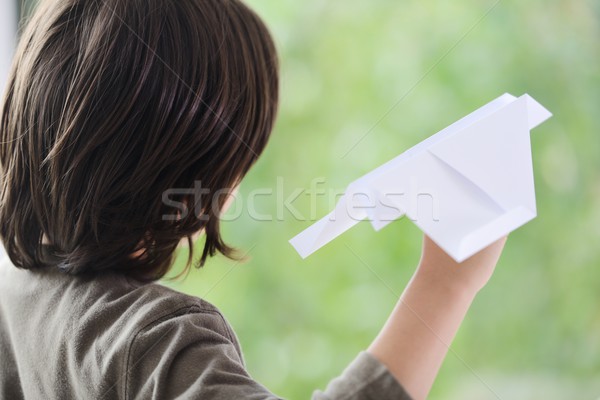 Boy flying a paper airplane from home window Stock photo © zurijeta