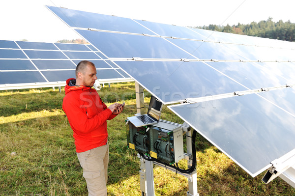 Engineer working with laptop by solar panels, talking on cell phone Stock photo © zurijeta