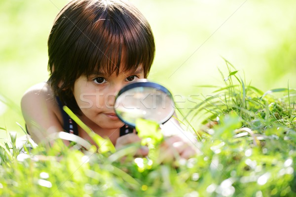 Happy kid exploring nature with magnifying glass Stock photo © zurijeta