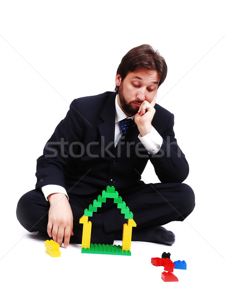 Young mane wearing suit is making a house with cubes toys Stock photo © zurijeta