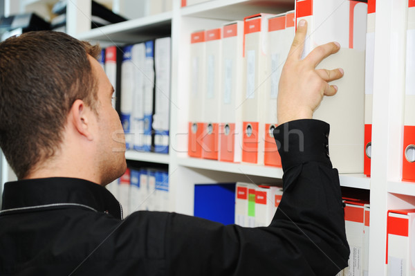 Man working at office putting folders together on shelves Stock photo © zurijeta
