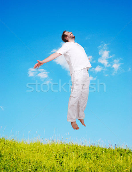 Happy young mane in white jumping on beautiful meadow Stock photo © zurijeta