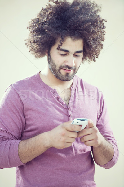 Jóképű fiatalember göndör haj okostelefon fiatal jóképű férfi Stock fotó © zurijeta