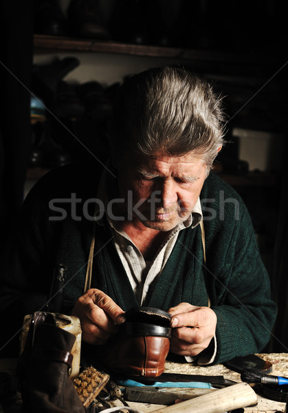 Old man, shoemaker, repairing old handmade shoe in his workshop Stock photo © zurijeta
