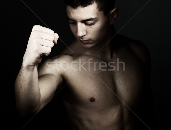 Fiatal férfi mutat bicepsz ököl kéz Stock fotó © zurijeta