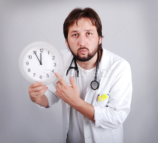  male doctor holding out an alarm clock ticking ever closer to 12  Stock photo © zurijeta