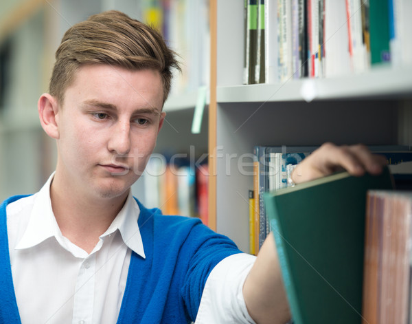 Stock photo: Happy young students studying in college library picking a book 