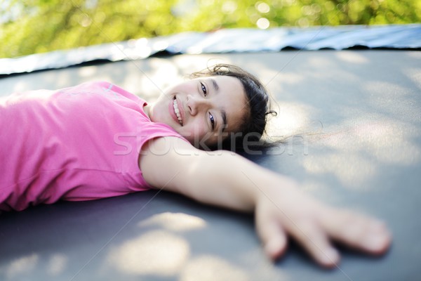Portrait of a smiling little girl lying on trampoline Stock photo © zurijeta