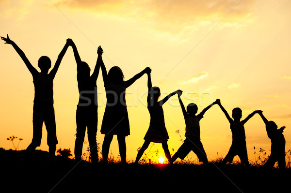 Stock photo: Silhouette, group of happy children playing on meadow, sunset, summertime