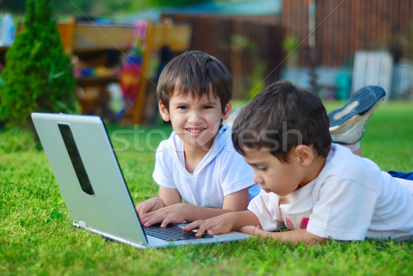 Two cute children laying in grass on laptop Stock photo © zurijeta