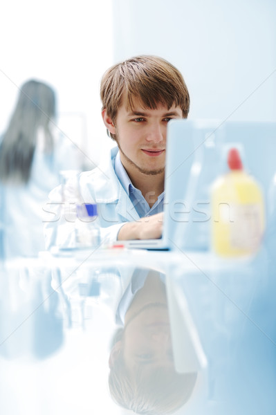 Stock photo: Young medical scientist working in modern lab, research with tubes and notebook
