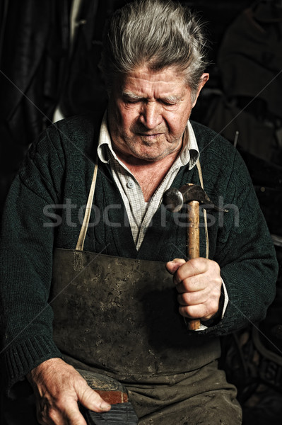 Old man, shoemaker, repairing old handmade shoe in his workshop Stock photo © zurijeta