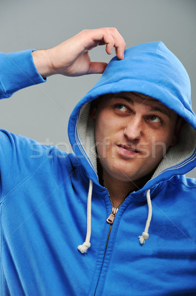 Stock photo: Young man in hooded sweatshirt scratching his head