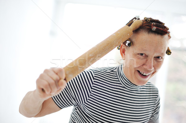 Senior woman with a rolling pin and curlers on hair Stock photo © zurijeta