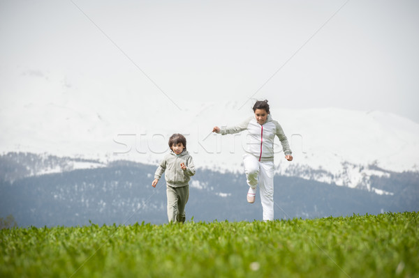 Stock photo: Boy and girl running and jumping on spring field in Alps