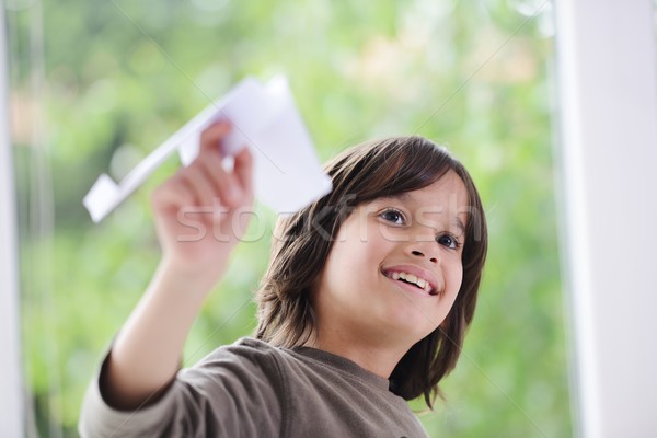 Boy flying a paper airplane from home window Stock photo © zurijeta