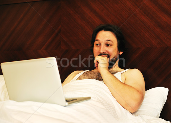 Man on laptop in bedroom looking at something Stock photo © zurijeta