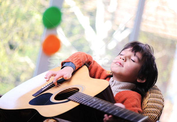 Stock photo: Kid playing guitar at home