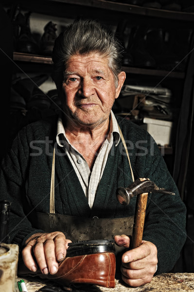 Old man, shoemaker, repairing old handmade shoe in his workshop Stock photo © zurijeta