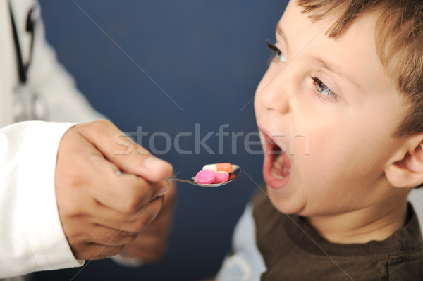 Doctor giving a child a spoon filled with pills Stock photo © zurijeta
