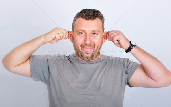 Young funny man holding his ears Stock photo © zurijeta