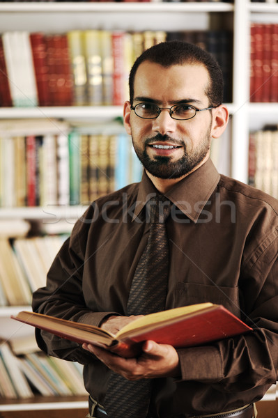 Stock photo: Young happy man standing in university library reading and smiling