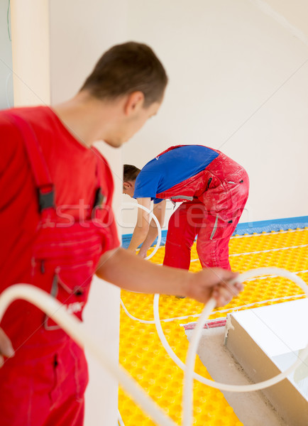 Manual worker installing underfloor heating and colling pipes Stock photo © zurijeta