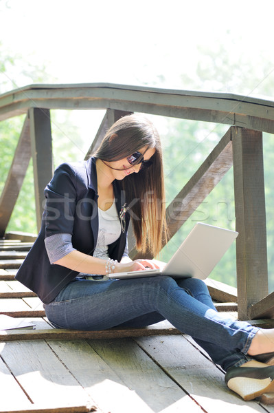 Female studing using laptop while sitting on a wooden bridge in nature Stock photo © zurijeta