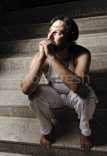 Thoughtful man on black background in low key, sitting on stairs Stock photo © zurijeta