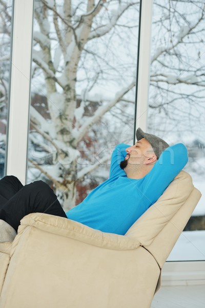 Young man relaxing on a white sofa at home by winter snow time Stock photo © zurijeta