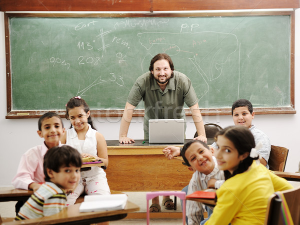 Stock photo: Teacher in classroom with his little happy students