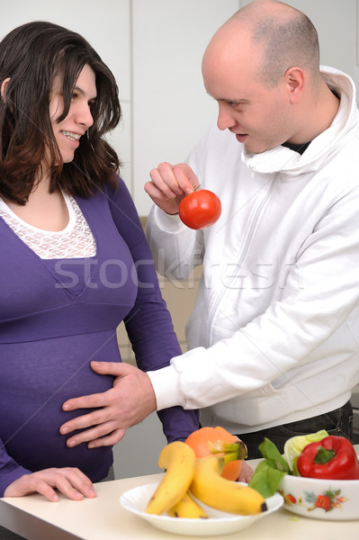 Portrait of a handsome man giving potato to his pregnant wife in kitchen Stock photo © zurijeta