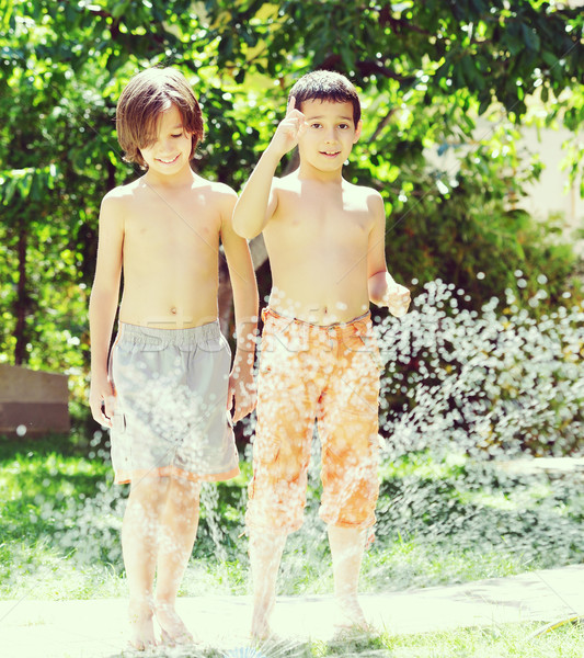 Children playing and splashing with water sprinkler on summer gr Stock photo © zurijeta