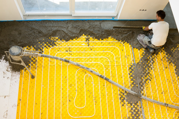 Plasterer at indoor concrete cement floor topping with float Stock photo © zurijeta