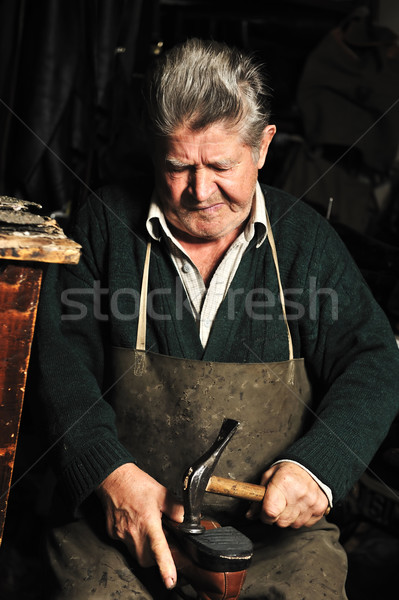 Elderly man, shoemaker repairing old shoe in his workshop Stock photo © zurijeta